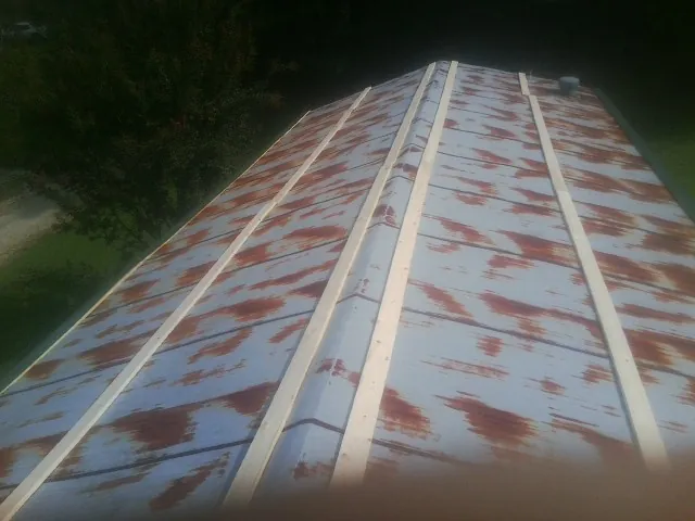 Rusted metal roof panels with new wood purlins before replacement — Storm Damage Roof Repair in Prairie City by Roofing Brothers